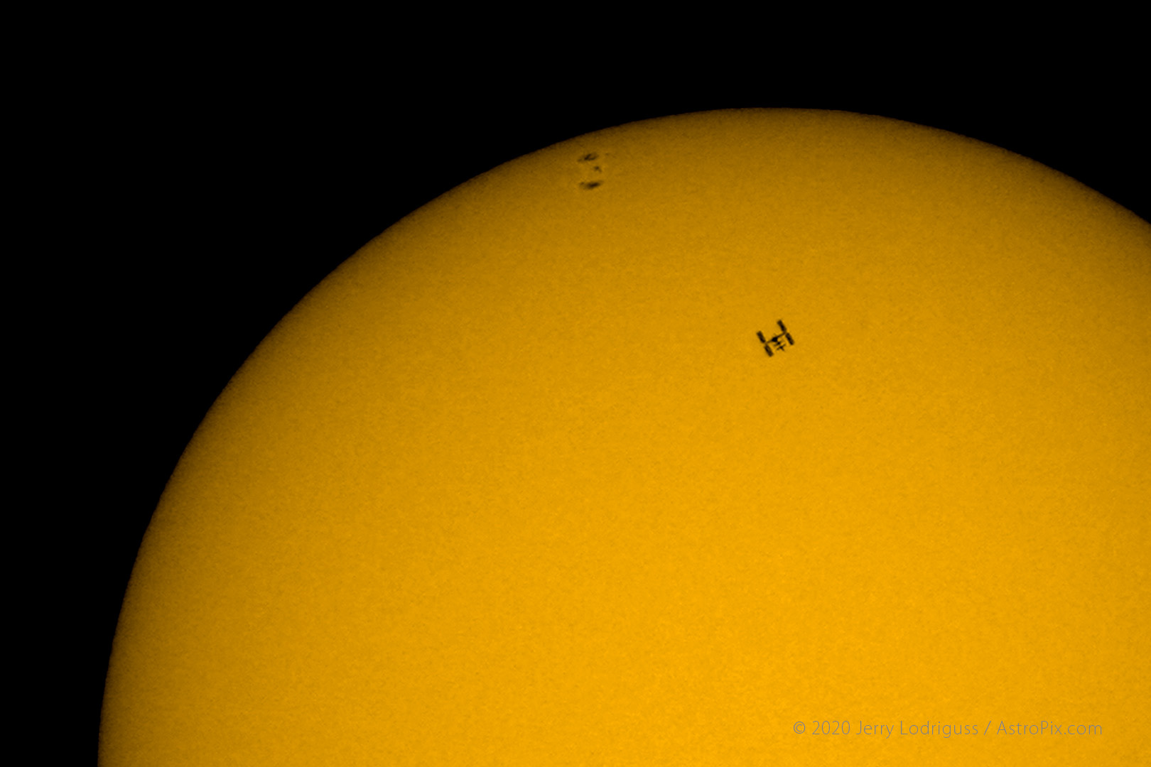 The International Space Station (ISS), with its new solar arrays, transits across the face of the Sun on July 8, 2007 at 14h 49m 54.40s EDT Sunspot group 963 is also visible on the eastern limb of the Sun, just rotating on.