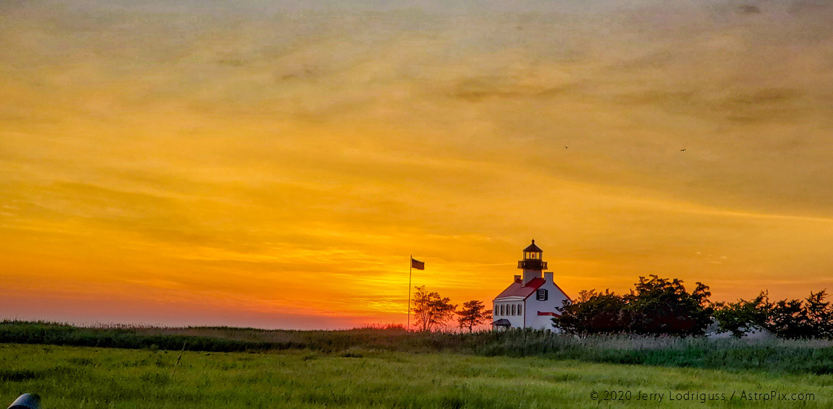 The sunset lights up the clouds behind the East Point Lighthouse on the Delaware Bay on July 18, 2020.<br /><br />Galaxy S10 cell phone<br />4.3mm focal length lens<br />1/125th second exposure at ISO 50 at f/2.4