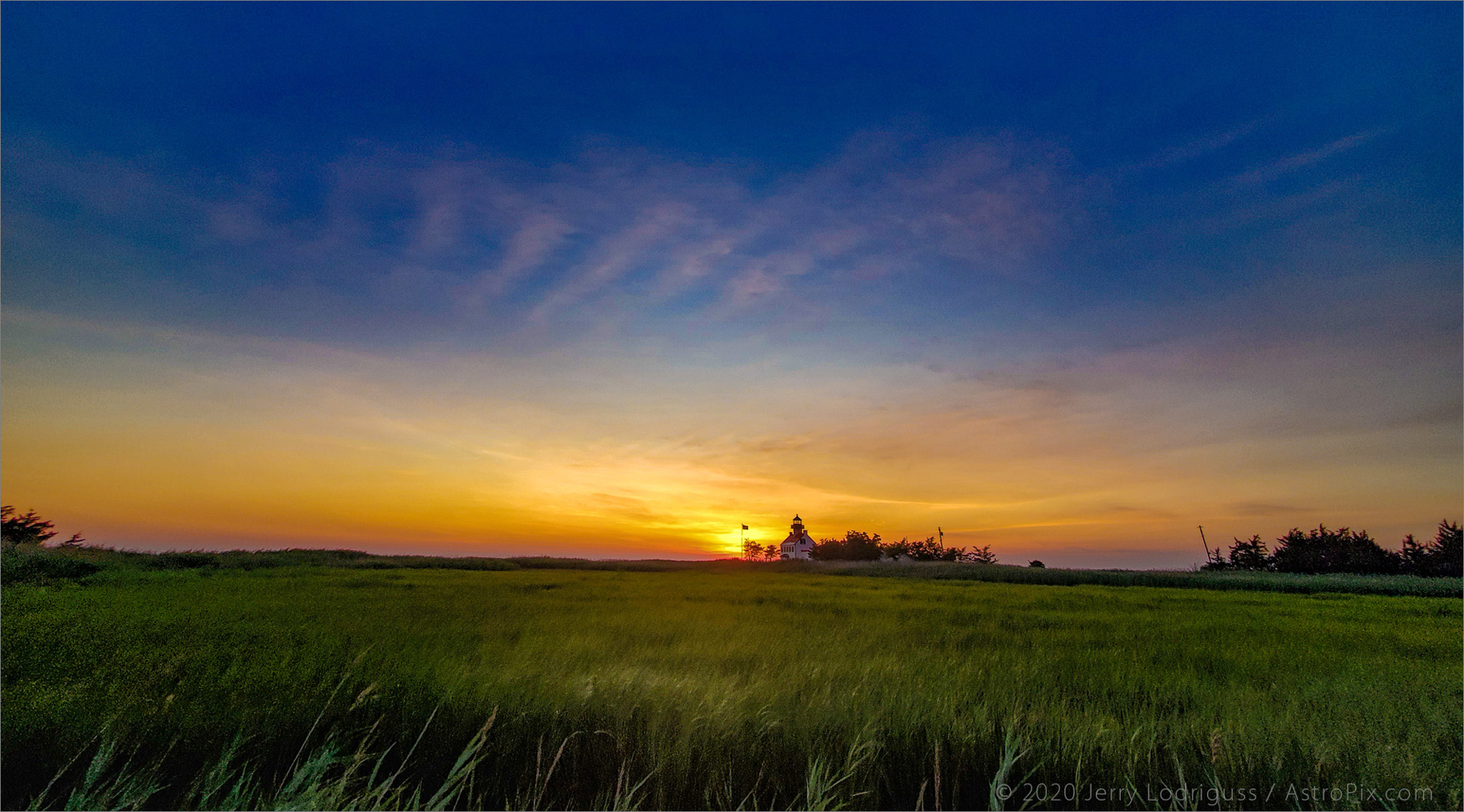 The sunset lights up the clouds behind the East Point Lighthouse on the Delaware Bay on July 18, 2020.<br /><br />Galaxy S10 cell phone<br />1.8mm focal length lens<br />1/120th second exposure at ISO 64 at f/2.2