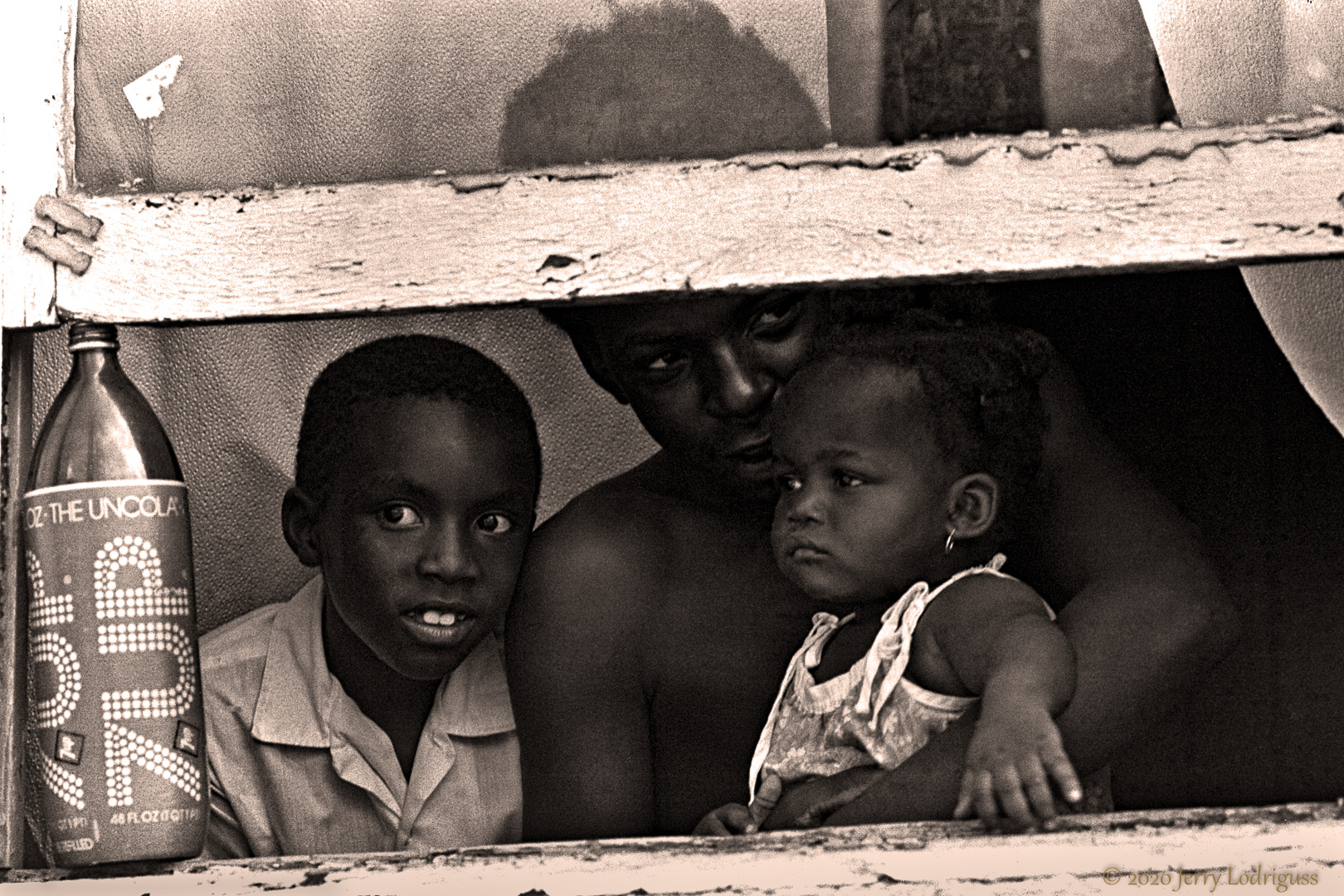 A father and his children watch a police murder investigation in the Desire-Florida Housing Project, Ninth Ward, New Orleans.