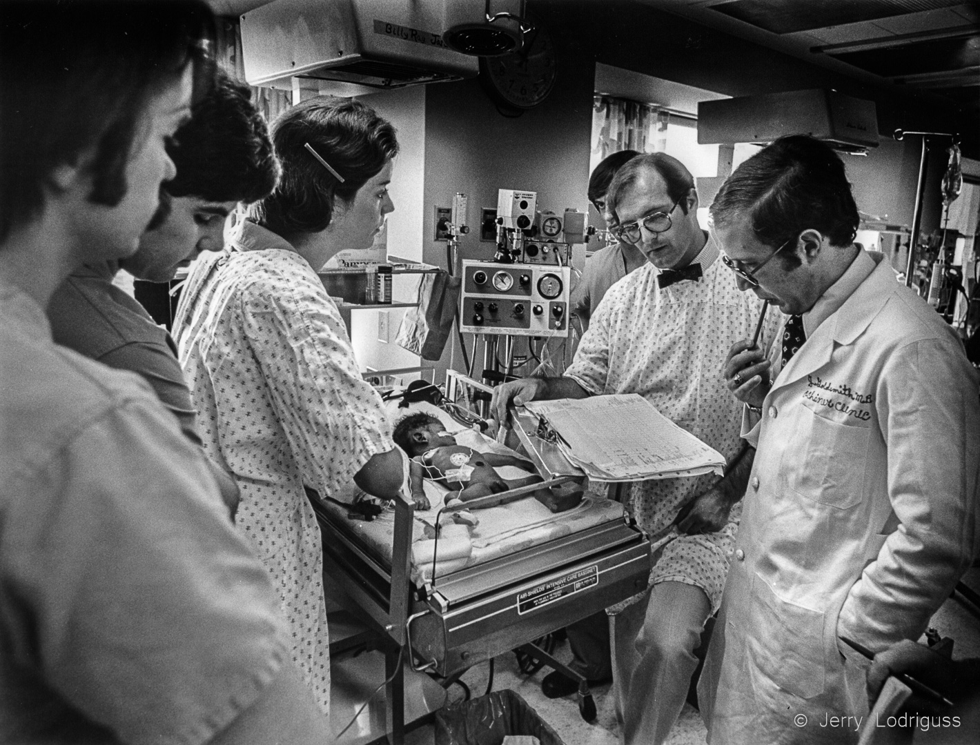 During daily rounds, Dr. Goldsmith (right) and staff doctors pause to ponder the baby's condition. Tests showed irreversible brain damage and all parties, including the child's mother, agreed after 17 days to turn off the life support systems, and the child died. "We're not God" said Dr. Goldsmith.
