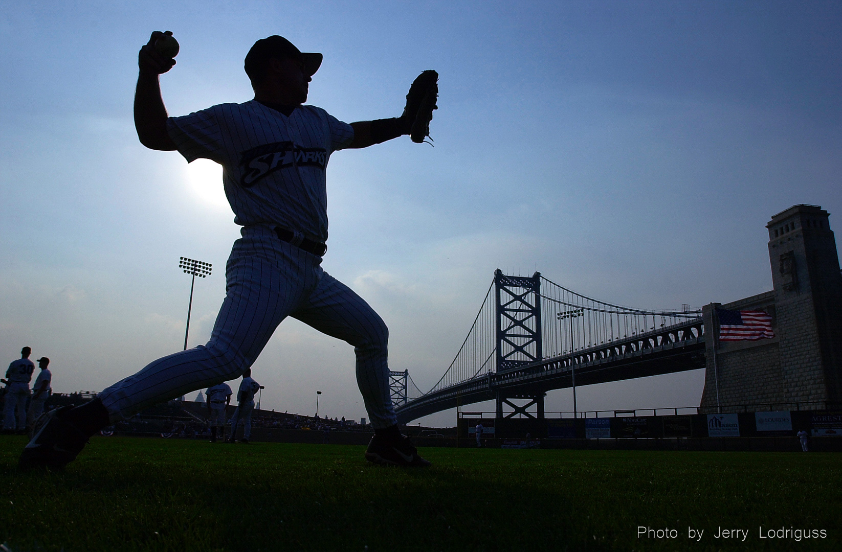 With the Benjamin Franklin bridge in the outfield, Camden Riversharks catcher Joe Goodwin warms up before the start of the first home game at their new ballpark, Campbell Field in Camden, New Jersey on May 11, 2001.