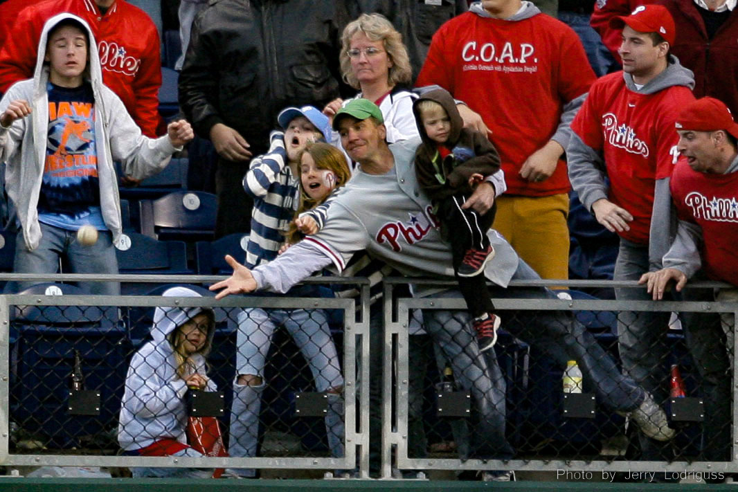 A fan holding a young child reaches over the railing 20 feet above the right field trying to catch a hit by Chase Utley in the tenth inning. The ball went off the wall and Utley ended up with a double. Utley, however, was left on base as the Cubs recorded the final out. The Phillies left 15 runners on base in the loss to the Cubs, but, the child was not dropped.