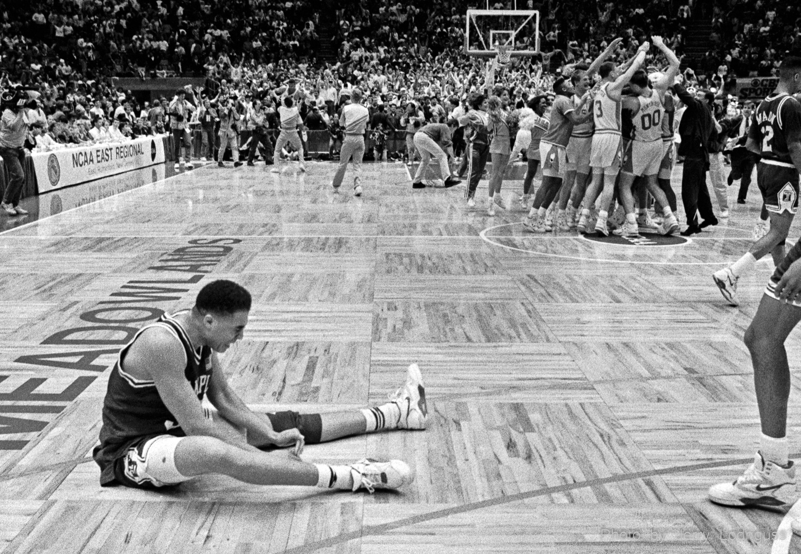 Donald Hodge sits on the court dejected as North Carolina celebrates their victory over Temple in the Eastern Regional Finals in the Meadowlands, NJ on March 24, 1991.