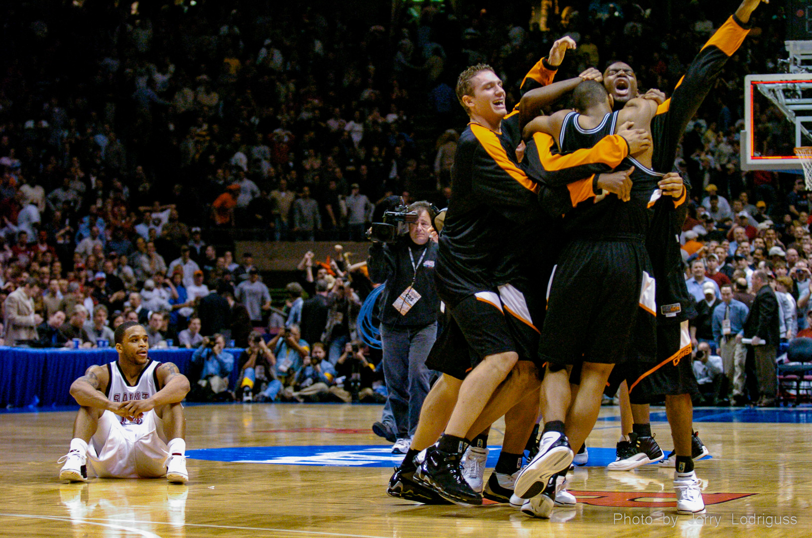 St. Joes Hawks' Jameer Nelson sits on the court dejected as the Oklahoma State Cowboys celebrate their win over the Hawks in the east regional finals of the NCAA men's basketball tournament on Saturday March 27, 2004. Nelson had missed the last shot for the Hawks, who had not lost a game all year until this final defeat which crushed their dream of going to the Final Four.