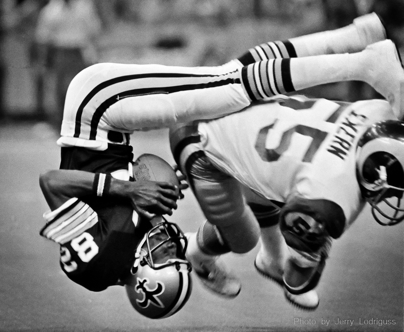 New Orleans Saints' Ike Harris flips upside down but holds on to the ball for a 16-yard gain during the fourth quarter of Saints - Rams game on November 25, 1980 in the Louisiana Superdome. The Rams' Carl Ekern made the hit on the play, and the Rams went on to win 27-7 as the Saints lost their 12th game.