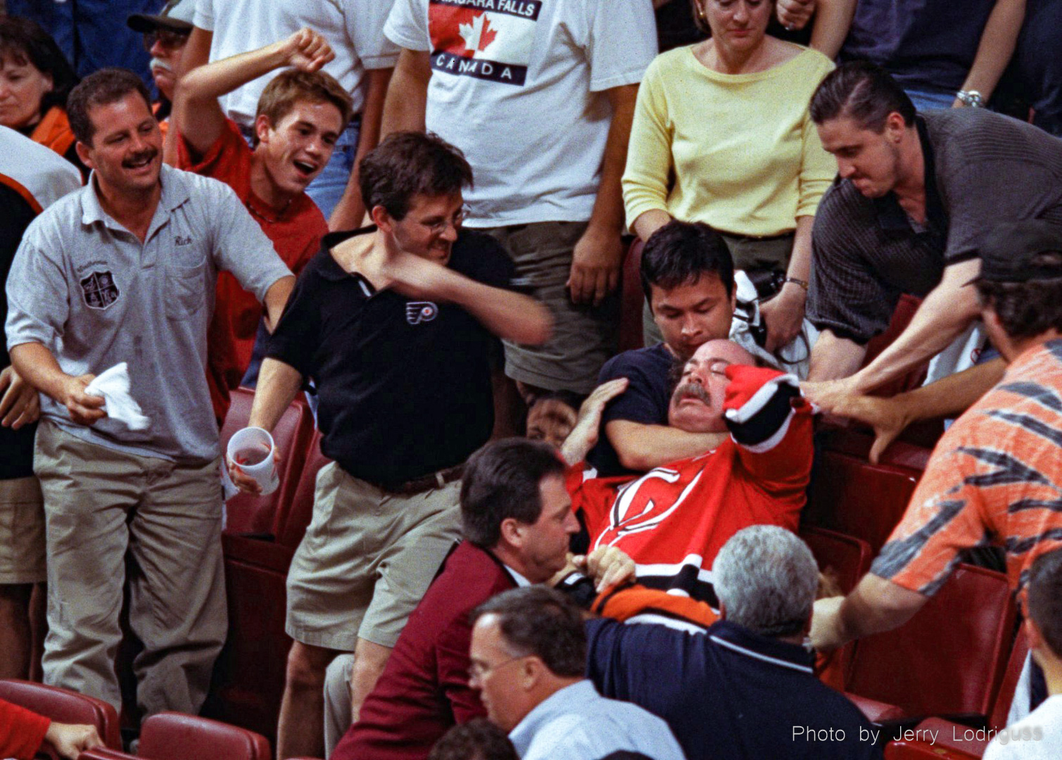 A Devils' fan is choked from behind by a Flyers' fan trying to hold him back as another gets set to backhand him during a fight between rival fans during closing minutes of Flyers 4-1 loss to the Devils in game one of the NHL Eastern Conference Playoff Finals.